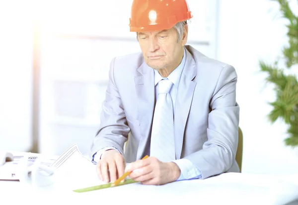 Ingenieur de leeftijd rekening te houden met plannen van tekening en corrigeert ze. — Stockfoto