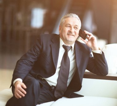 Oturma ve telefonda konuşurken gülümseyen iş adamı