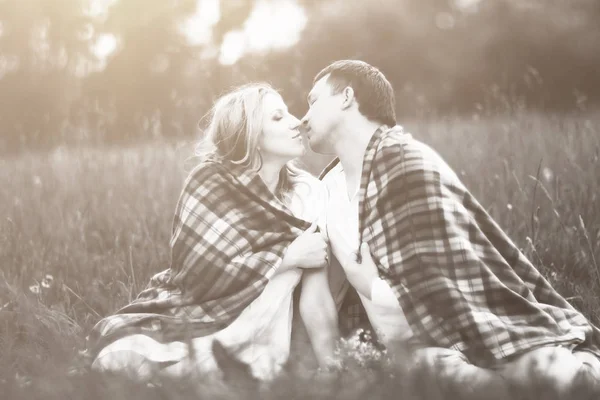 Gelukkige paar - zwangere vrouw en haar man in het park is voorzien van een warme deken — Stockfoto