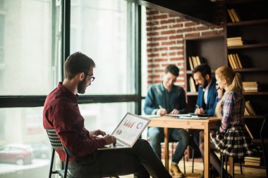 Ticari Yönetici dizüstü bilgisayarında mali grafiklerle çalışıyor.