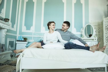 sevgi dolu çift yatak odasında yatağın üstüne oturuyor