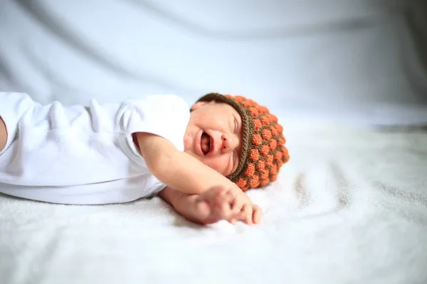 Neugeborenes Baby in Strickmütze auf weißem Laken liegend. — Stockfoto