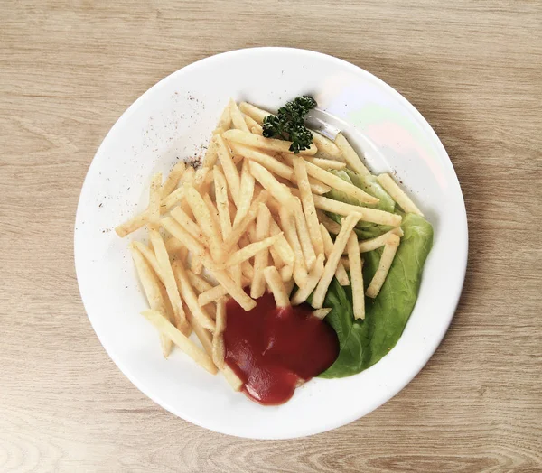 Les frites, la sauce et la salade dans l'assiette en bois — Photo