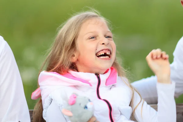 Glückliches kleines Mädchen mit Stofftier sitzt auf einem Park — Stockfoto