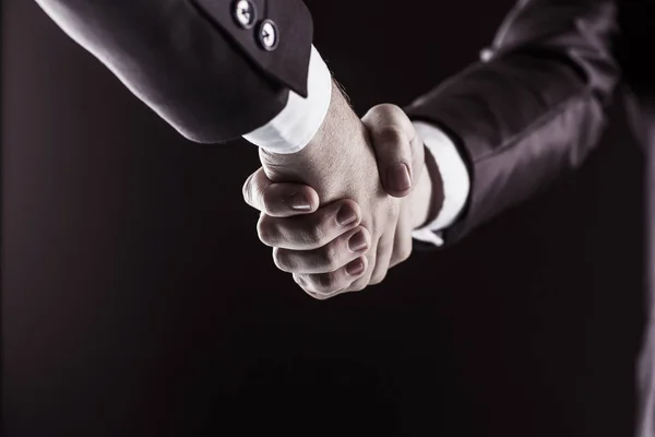 Concepto de una asociación fiable: un primer plano del apretón de manos de los socios comerciales sobre un fondo negro . —  Fotos de Stock