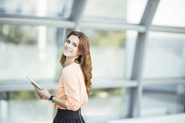 Succesvol zakenvrouw met digitale tablet staan in de buurt van een groot raam in een modern kantoor — Stockfoto