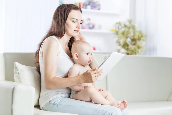 Gelukkig moeder tonen van zijn jaar-oude baby foto's op digitale tablet — Stockfoto