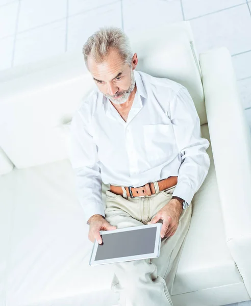 Successful businessman with digital tablet sitting in modern office chair. — Stock Photo, Image
