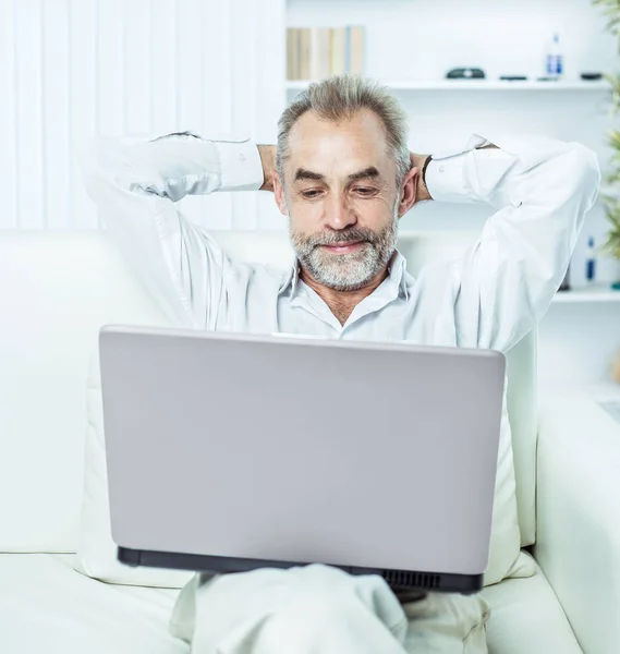 Framgångsrik affärsman arbetar på bärbar dator sitter på soffan i moderna kontor. — Stockfoto