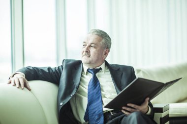 başarılı bir iş adamı özel ofisinde kanepede oturan yeni bir sözleşme dikkate alınarak