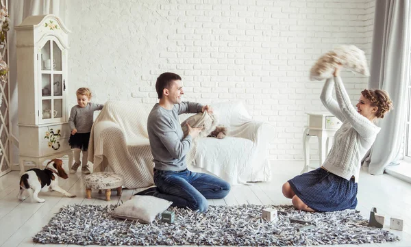 Mutlu bir aile ve geniş oturma odası yastıklar ile oynayan evde beslenen hayvan köpek — Stok fotoğraf