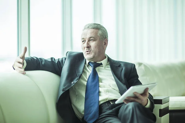 Successful businessman with digital tablet sitting on the sofa in the private office — Stock Photo, Image