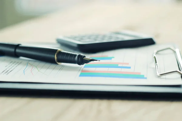 Ручка, калькулятор и финансовый график на рабочем месте предприятия — стоковое фото