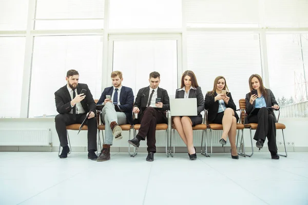 Equipo de negocios con portátil y smartphone sentado en el sofá frente a la reunión de trabajo — Foto de Stock