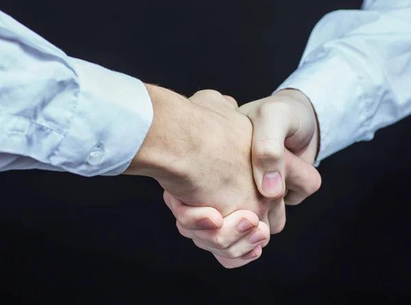 Konzept einer verlässlichen Partnerschaft: Handschlag von Geschäftspartnern aus nächster Nähe auf schwarzem Hintergrund. — Stockfoto