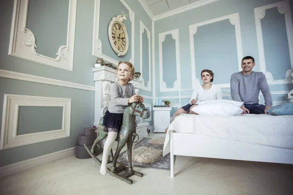 Menina balançando em um cavalo de madeira no quarto de seus pais — Fotografia de Stock