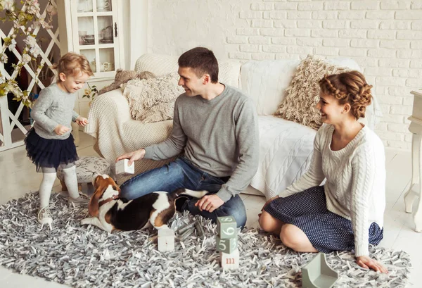 Família feliz brincando com um cão de estimação na espaçosa sala de estar — Fotografia de Stock
