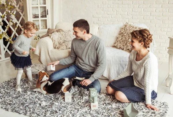 happy family playing with a pet dog in the spacious living room