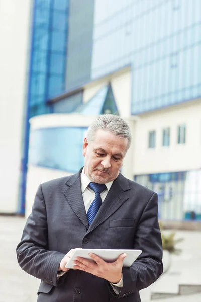 Framgångsrik affärsman med digital tablett på bakgrund av kontorsbyggnad — Stockfoto