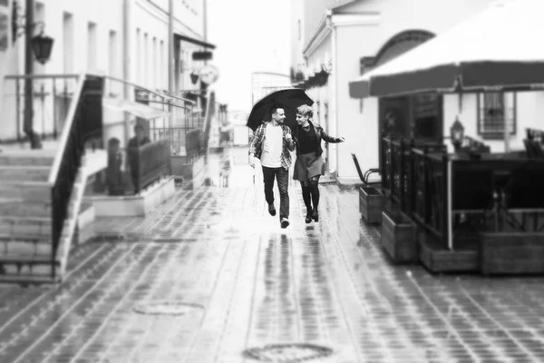 Concept of love: loving couple under an umbrella walking down the street of the city.black-and-white photo in retro style — Stock Photo, Image