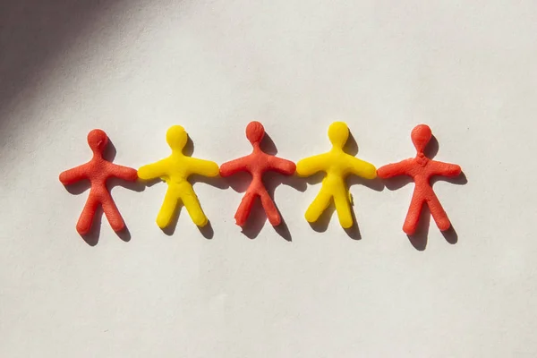 Silhouettes of people who hold each others hands made of dough on a light background — Stock Photo, Image