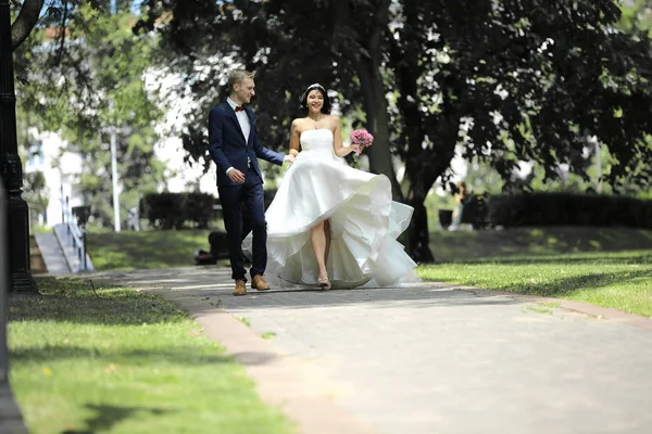 Dag van de bruiloft die de mooie bruid en bruidegom door het park lopen — Stockfoto