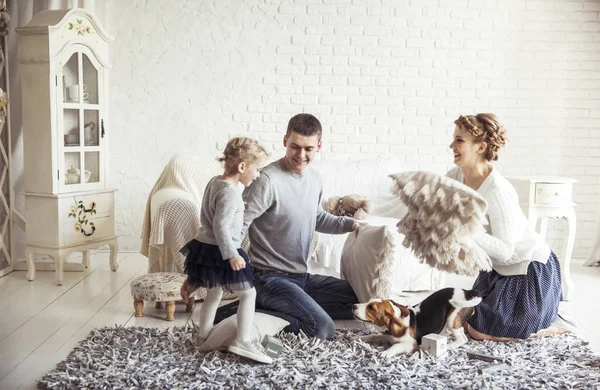 Familia feliz y perro mascota jugando con almohadas en la amplia sala de estar — Foto de Stock