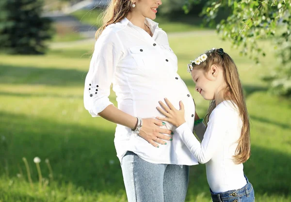 Concetto di maternità - madre incinta e figlioletta su un — Foto Stock