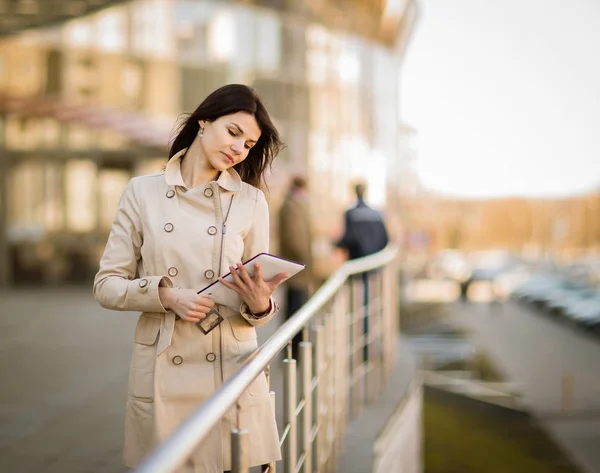 Mujer de negocios moderna trabajando en una tableta digital, de pie junto a un edificio de oficinas —  Fotos de Stock