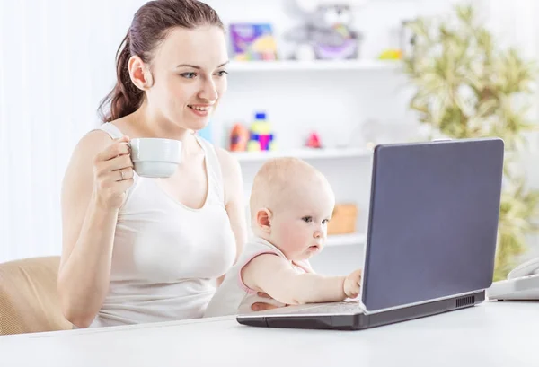 Nuori äiti ja vauva käyttävät kannettavaa tietokonetta kommunikoimaan isoäidin kanssa skypen kautta , — kuvapankkivalokuva