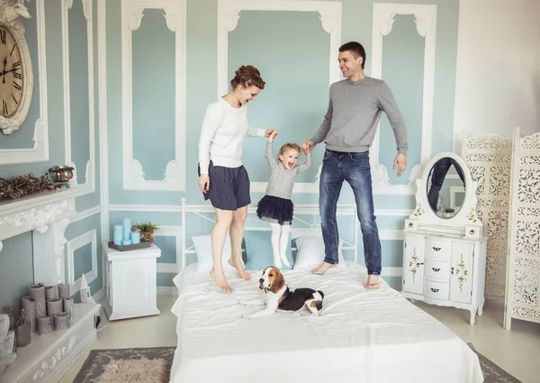 Concepto de felicidad familiar: padres cariñosos jugando con la hija en la cama en el dormitorio — Foto de Stock