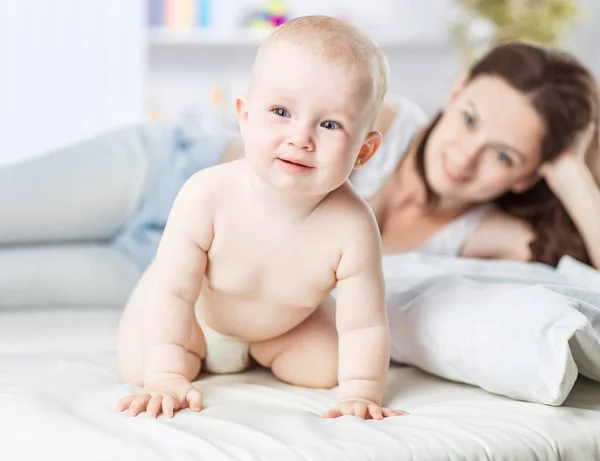 Portrait of happy mother and year-old baby on the bed in the bedroom — Stock Photo, Image