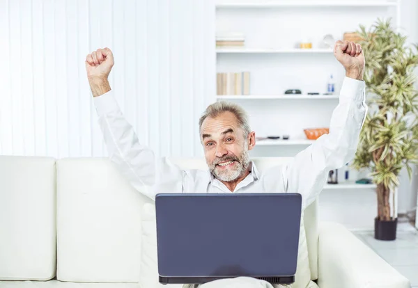 Begeisterter Geschäftsmann mit offenem Laptop auf Sofa im modernen Büro. — Stockfoto