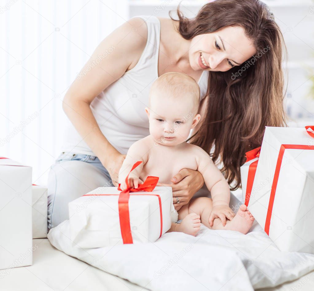 happy mothers her infant baby consider holiday shopping, folded on the sofa in the room