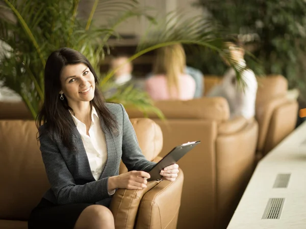 Succesvol zakenvrouw met documenten zittend in een stoel in een lobby van een modern kantoor — Stockfoto