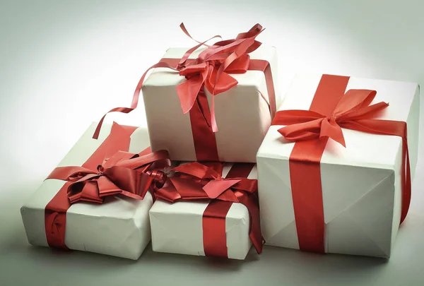 Elegant gift boxes with red satin ribbon wrapped in paper. — Stock Photo, Image