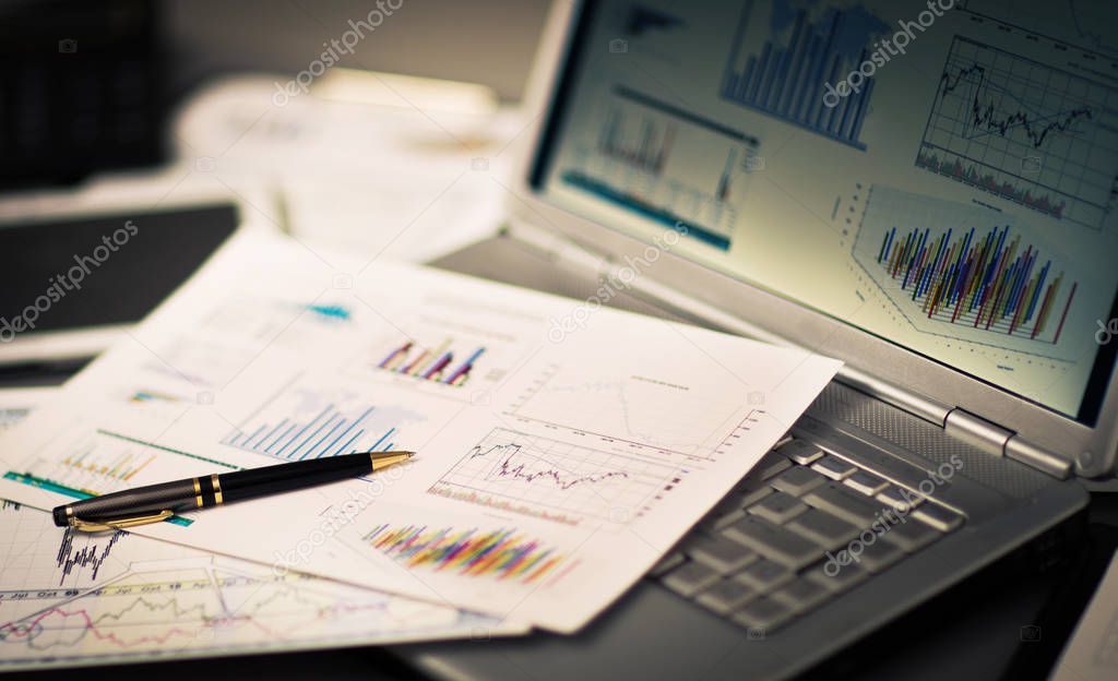 Businessman analyzing investment charts with laptop.