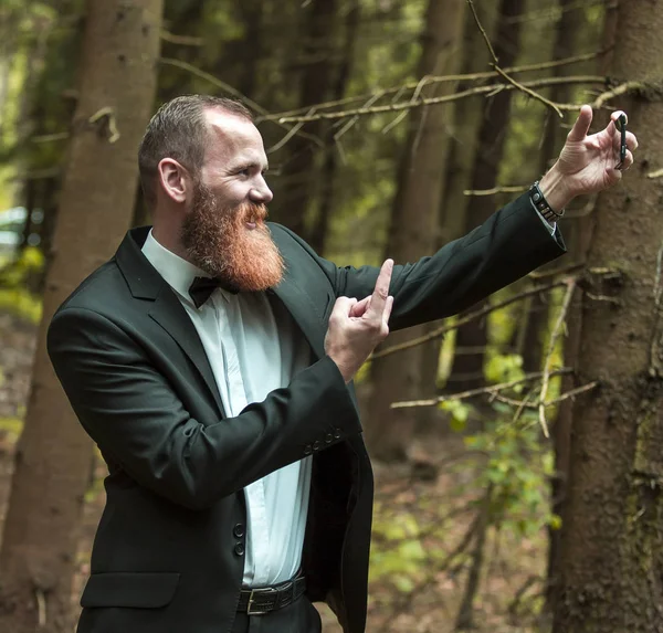 Σίγουρος ο άνθρωπος σε ένα επαγγελματικό κοστούμι με μια selfie στο δάσος. — Φωτογραφία Αρχείου