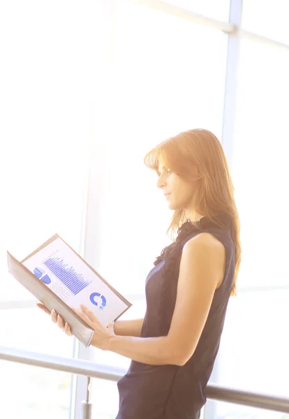 Modern business woman with financial charts while standing near a large office window — Stock Photo, Image