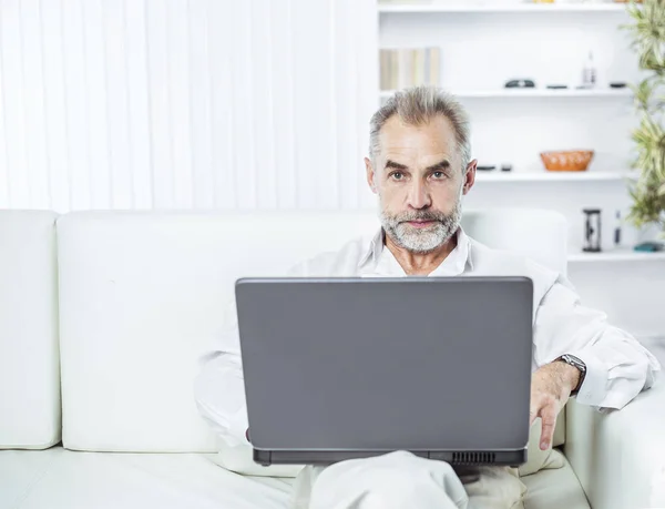 Framgångsrik affärsman arbetar på bärbar dator sitter på soffan i moderna kontor. — Stockfoto