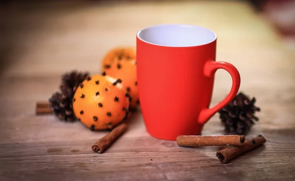 Taza roja de Navidad, palos de canela y naranjas en el fondo de madera —  Fotos de Stock