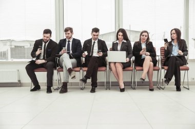 bir smartphone ve modern ofis lobisinde otururken dizüstü kullanarak internette bilgi arayan iş takım