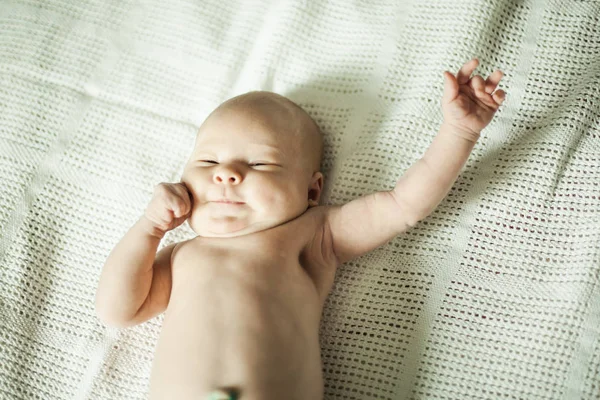 Niedliches lächelndes Baby liegt auf weißer Decke. — Stockfoto