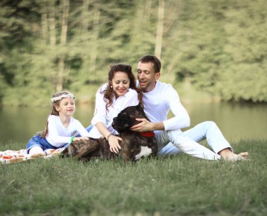 Güneşli bir yaz gününde piknikte köpekli mutlu bir aile. pregn
