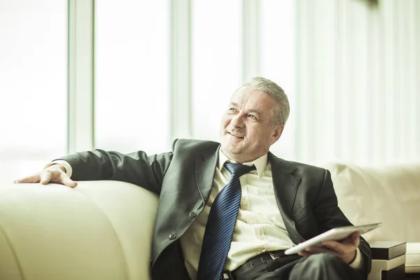 Experienced lawyer with digital tablet sitting on the sofa in the private office — Stock Photo, Image