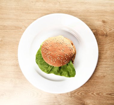 Hamburger ahşap arka plan üzerinde beyaz bir plaka üzerinde