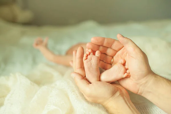 .Gelukkig moeder knuffelen de benen van een pasgeboren baby. — Stockfoto