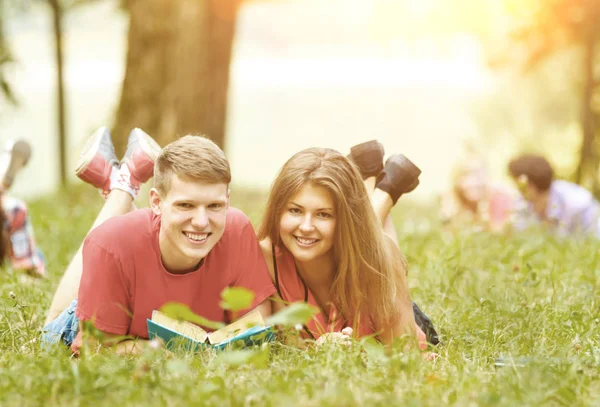 Par framgångsrika elever med en lärobok i en Park — Stockfoto