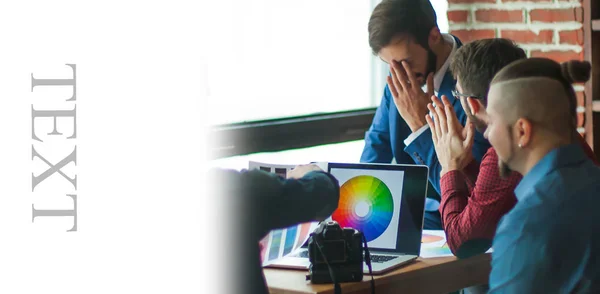 Eine Gruppe kreativer Designer diskutiert die Farbpalette im Büro, links Platz für Werbetexte — Stockfoto