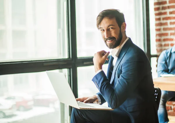 Employee with a laptop near a large window in the office — Stock Photo, Image